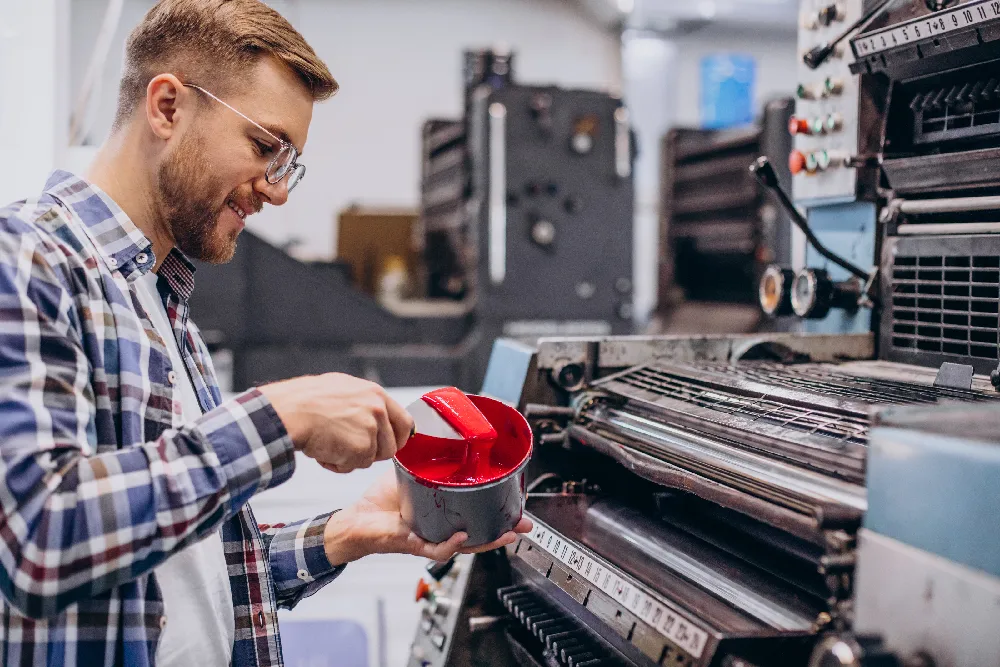 Man adding paint to a printing machine with care